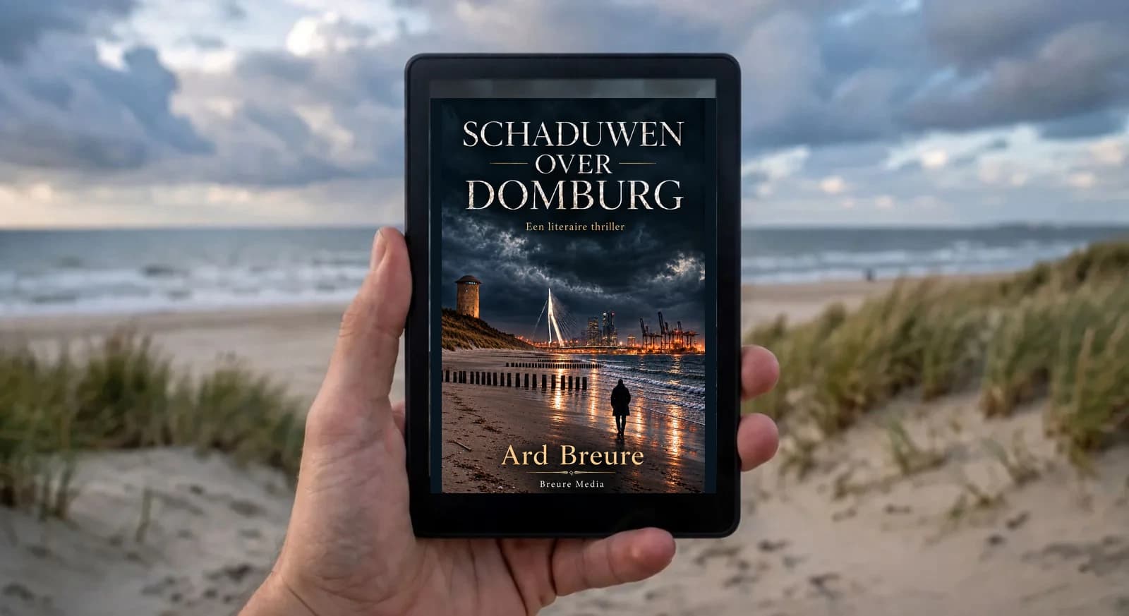 Kindle Paperwhite e-reader met de cover van Schaduwen over Domburg, op de achtergrond het Zeeuwse strand en de zee